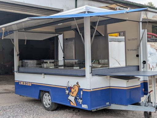 Ein mobiler Verkaufsstand in Blau und Weiß mit geöffnetem Dach und leeren Ablagen.